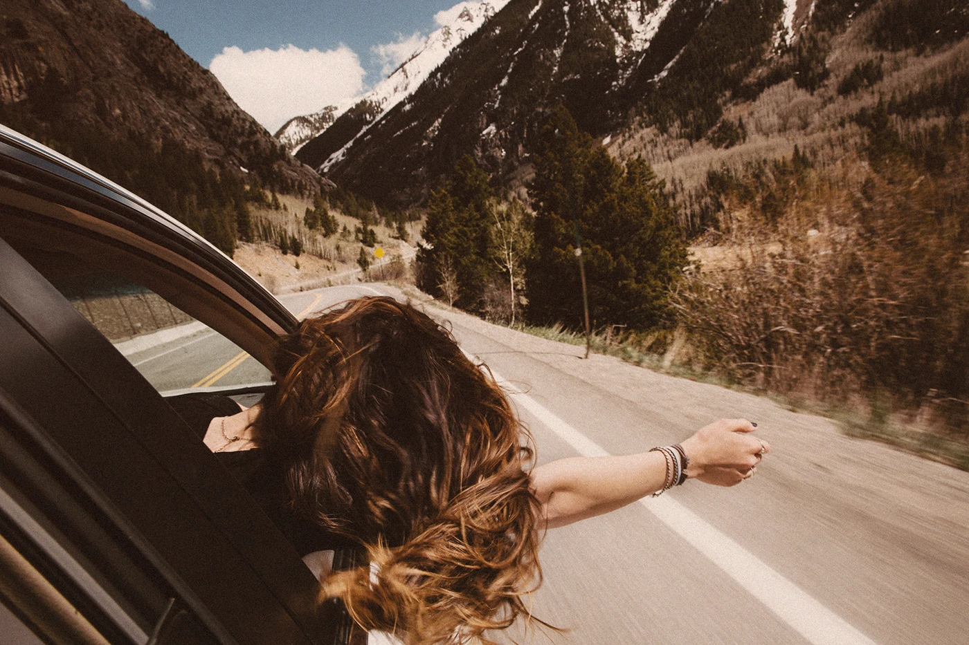 Road trip in summer, woman hanging outside car window